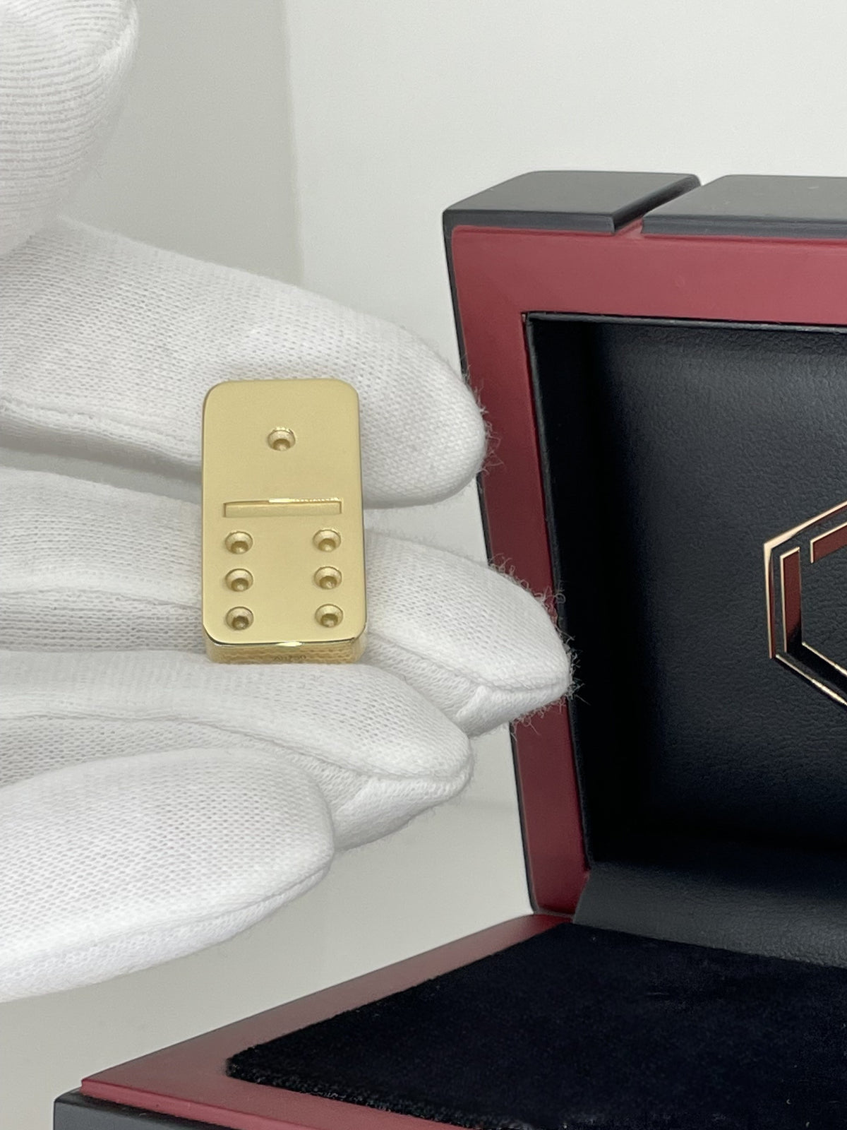 Solid 18-Karat Domino Tile lying in hand before case - Dominostein 18 Karat Gold liegend in der Hand